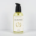 A bottle of Meadows & Myth's Fae Blossom body oil, featuring a clear glass bottle filled with pale yellow oil, a cream-colored label with gold botanical illustrations, and a black pump dispenser, set against a plain white background.
