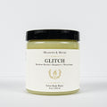A jar of Meadows & Myth's Glitch Velvet Body Butter with a black lid and a cream-colored label, set against a plain white background.
