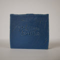 A rectangular blue bar of soap standing upright on a light gray background, embossed with the brand name 'Meadows & Myths'.